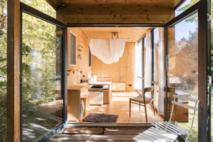 The interior of a tiny house in a wooded area with sunlight shining in