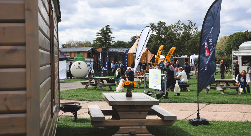 a scene of people walking around the glamping show
